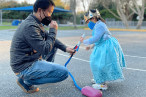 Father and daughter playing outside, wearing masks