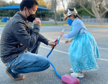 Father and daughter playing outside, wearing masks